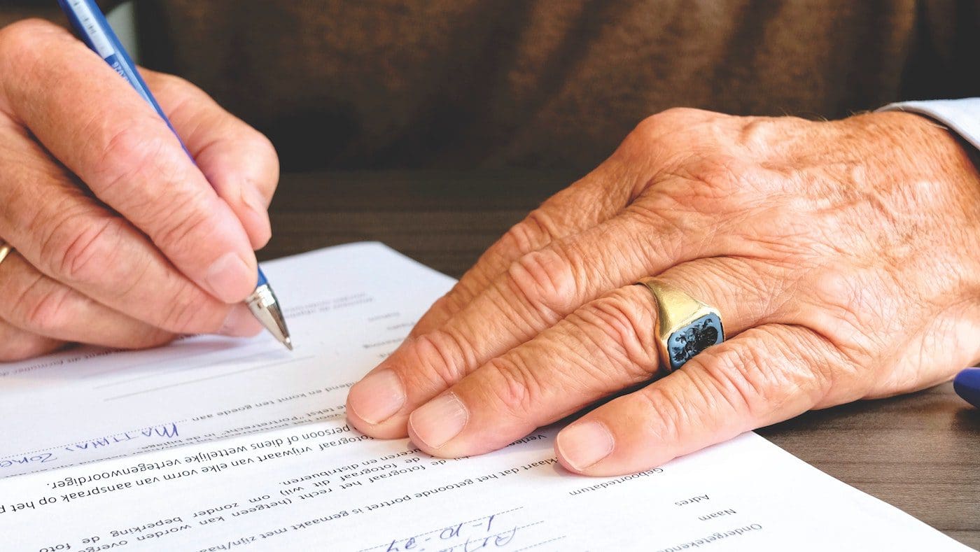 older man signing funeral papers